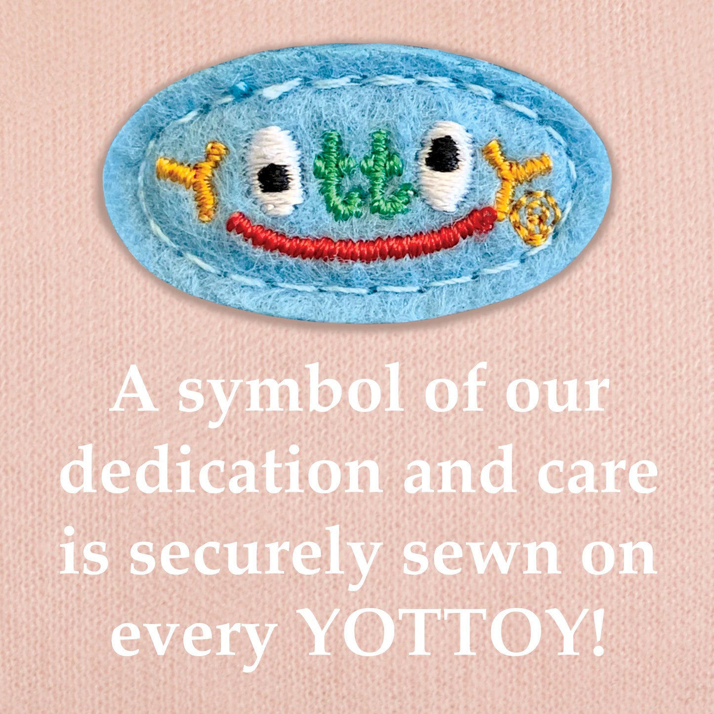 The image shows an embroidered blue YOTTOY logo in multicolored stitching with a small red smile, sewn onto pink knit fabric. Below the emblem, bold white text reads: “A symbol of our dedication and care is securely sewn on every YOTTOY!”