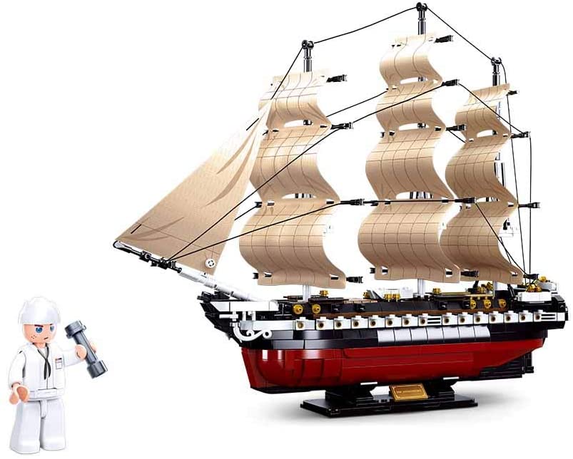 The USS Constitution 1794 Navy Frigate comes in a large, features a finished ship sailing on a white background, with three detailed masts, off-white sails, and a red-and-black textured hull. A small illustration in the bottom left corner depicts a sailor holding a weight.
