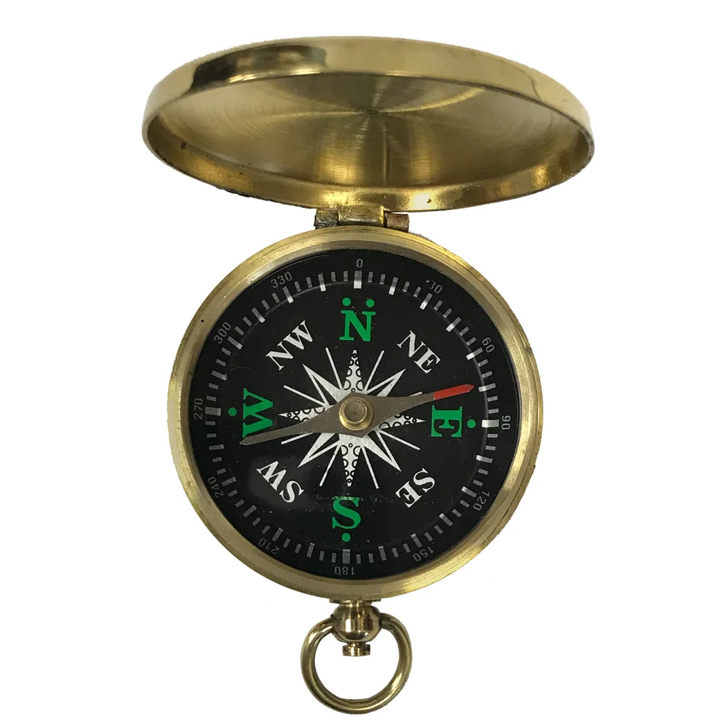 A small, round brass pocket compass shown on a white background. It has a smooth, polished case about 2 inches wide with a flip‑top hinged lid. The open compass reveals a glass‑covered black face with raised white directional markings, a brass needle, a small side lever to lock the needle, and a brass ring for attaching a chain.