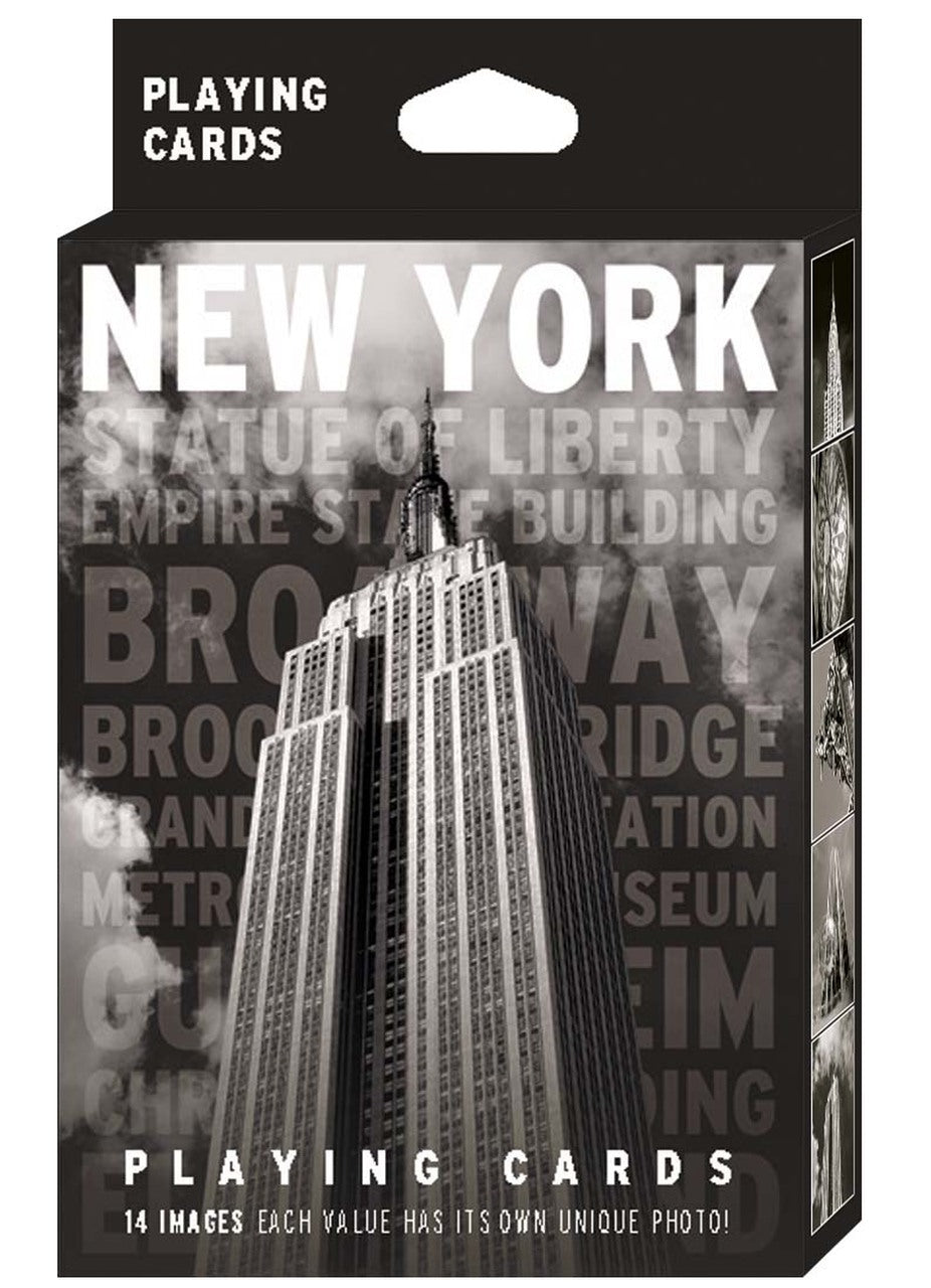 New York Black & White Playing Card Pack: The image shows the packaging for a high‑contrast black‑and‑white deck. The front displays a bold photograph of the Empire State Building with “NEW YORK” in large white capital letters at the top and faint grey landmark names beneath. “Playing Cards” appears in white at both the top and bottom. The side panels feature additional black‑and‑white images of iconic New York buildings.