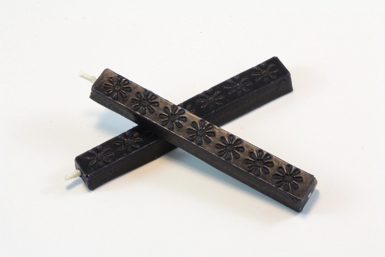The image shows two 4‑inch dark blue wax sticks on a white background. The wax appears hard and smooth, with subtle daisy‑like embossed patterns. When melted, it becomes thick and pliable, then cools to a slightly flexible, buttery finish designed to resist cracking in the mail.