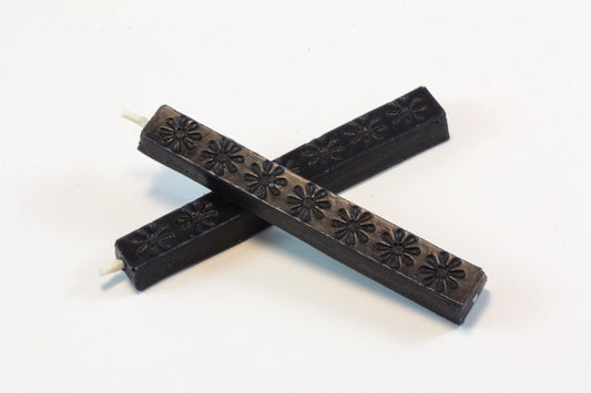 The image shows two 4‑inch dark blue wax sticks on a white background. The wax appears hard and smooth, with subtle daisy‑like embossed patterns. When melted, it becomes thick and pliable, then cools to a slightly flexible, buttery finish designed to resist cracking in the mail.