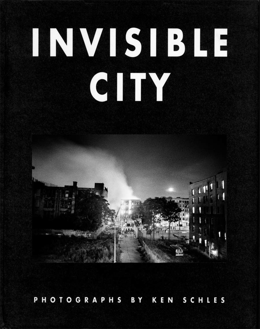 A minimalist, gritty book cover. The title appears in bold white block lettering against a black background above a high-contrast, grainy black-and-white photograph of a 1980s  Lower East Side New York City neighborhood at night. The lower portion is solid matte black, featuring “PHOTOGRAPHS BY KEN SCHLES” in clean, all-caps white type.