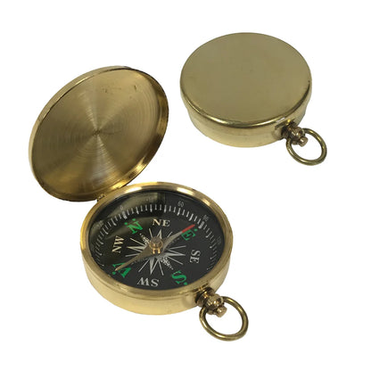 A small, round brass pocket compass shown on a white background. It has a smooth, polished case about 2 inches wide with a flip‑top hinged lid. Inside is a glass‑covered black compass face with raised white directional markings and a brass needle, plus a small side lever to lock the needle and a brass ring for attaching a chain. The image shows two views the compass open, and with the lid shut.