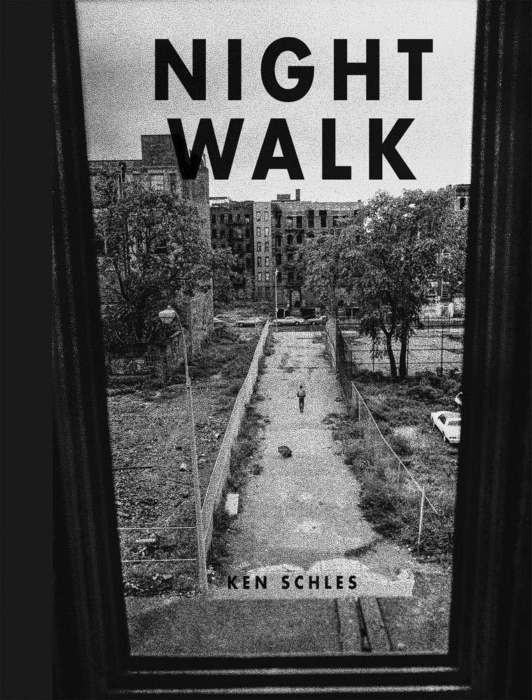 Night Walk by Ken Schles features a gritty, high-contrast black-and-white photograph viewed from above through a window. The image captures New York City tenement buildings beneath gray skies, with a central asphalt walkway flanked by worn grassy patches, each anchored by a solitary tree. A parked car and a lone figure on the path heighten the photograph’s stark, atmospheric mood. The title appears in bold black block lettering near the top of the cover, while the author's name is printed at the bottom.