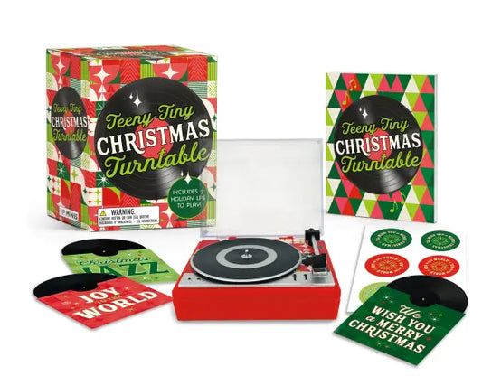 Product title: Tiny Holiday Turntable, Includes 3 Mini-LPs to Play. The image features a miniature holiday-themed turntable packaged in a whimsical red‑and‑green box. Three mini LPs are included, each with its own small illustrated album cover. The records play “We Wish You a Merry Christmas,” “Joy to the World,” and a third jazzy winter instrumental track.