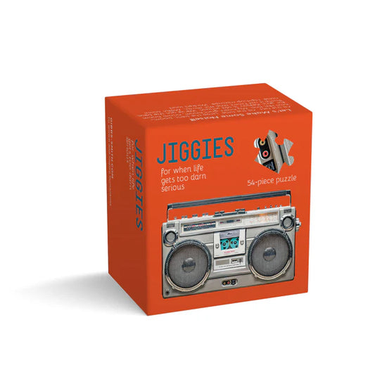 The box shows Jiggies in grey whimsical lettering on a bright red background, with the subtitle for when life gets too darn serious and a note that it’s a 54‑piece puzzle. The lower half displays a retro boombox in metallic grey.