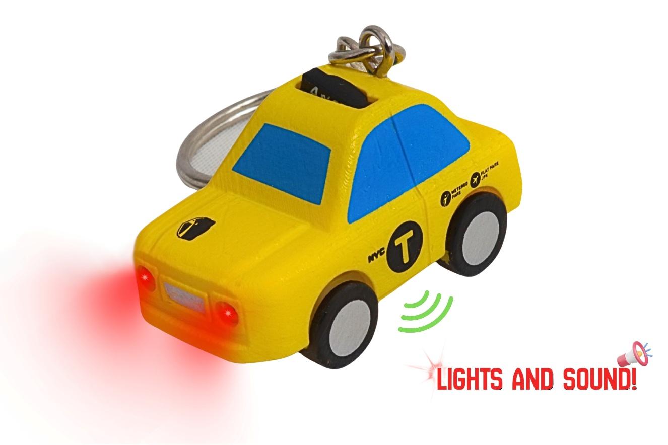 Yellow toy taxi keychain with blue windows and red light on a white background