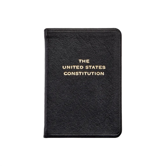 A black, leather‑bound book titled The United States Constitution, with the title stamped in gold lettering, shown against a clean white background.