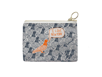 The item is a coin purse featuring a gold‑colored metal zipper with a round pull loop. The fabric is printed with a repeating pattern of grey pigeons drawn in a simple line‑art style. At the center, there is an orange‑outlined speech bubble containing the thin orange text “I love New York.” Directly beneath the text is a bright orange line‑drawing of a pigeon.