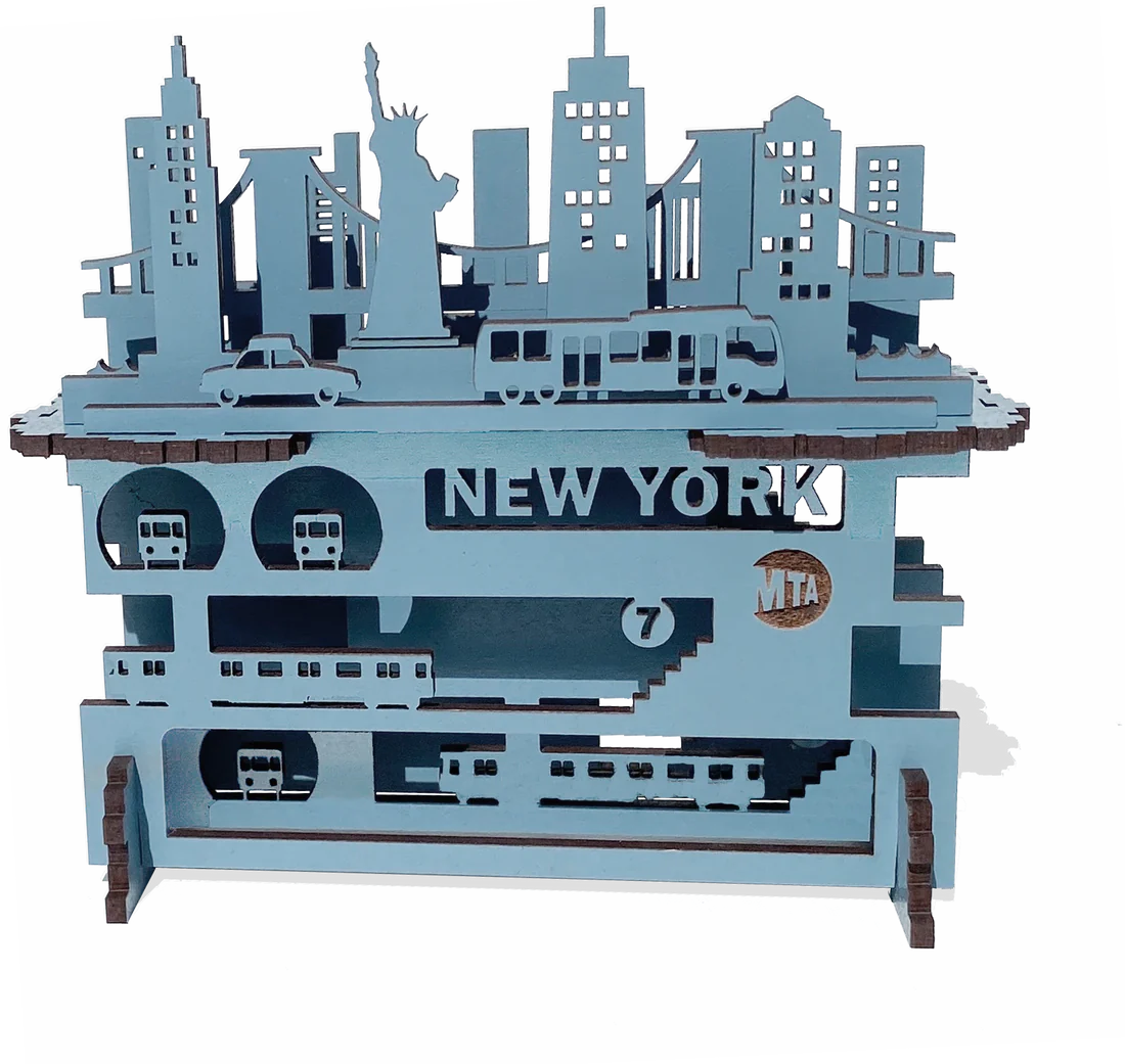 A layered wooden piece with a white background and raised blue shapes you can feel by touch. Smooth, thin wood forms New York City above and below the streets—buildings and landmarks on top, subway lines beneath—stacked to show the city’s depth and motion.