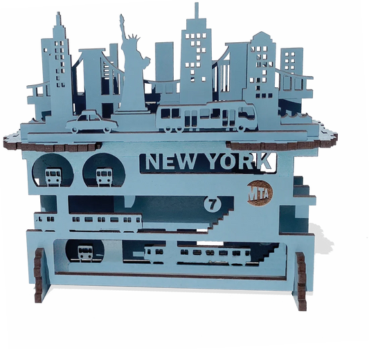 A layered wooden piece with a white background and raised blue shapes you can feel by touch. Smooth, thin wood forms New York City above and below the streets—buildings and landmarks on top, subway lines beneath—stacked to show the city’s depth and motion.