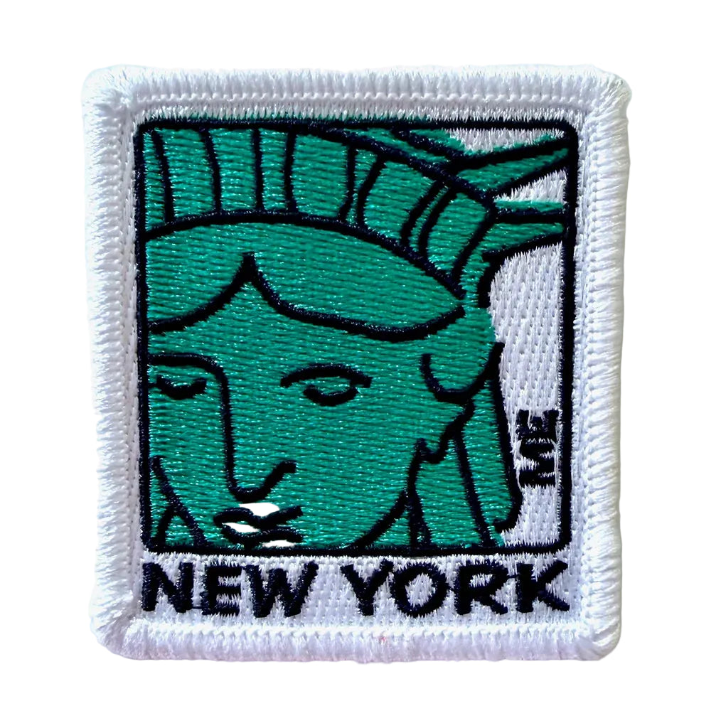 A square embroidered patch featuring a stylized green Statue of Liberty face with black outlines, a white border, and the word "NEW YORK" in black at the bottom.
