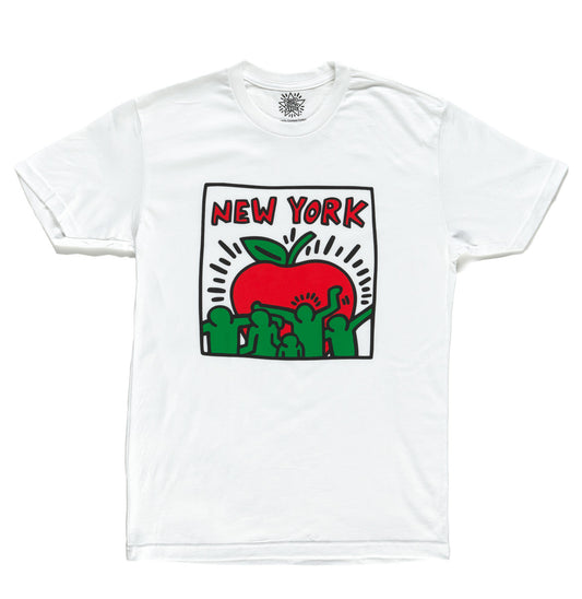 A soft white T shirt featuring a large, smooth graphic of a stylized apple in Keith Haring’s signature bold style. The apple is outlined with thick black lines and filled with lively red and green human figures that create a playful, energetic feel against the white background. The shirt has a classic unisex fit with short sleeves and a standard crew neckline. It’s lightweight, comfortable, and available in sizes from small to extra large.