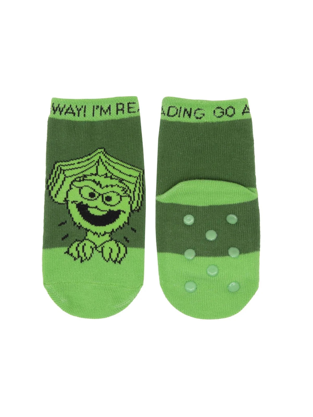 The photograph shows a pair of bright green Oscar the Grouch toddler socks. One sock features a simple line‑drawing illustration of Oscar’s face. The other sock is shown from the bottom, displaying rubberized anti‑slip dots across the sole..