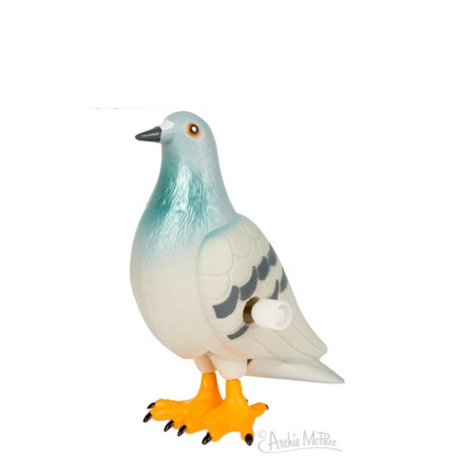 A glossy windup pigeon toy with a plastic body, featuring bold yellow, black, and white concentric‑circle eyes. Its light green-blue coloration fades into a white torso, and the white wings show curved gray feather details with the windup key protruding from one side. The feet are bright yellow with black talons.