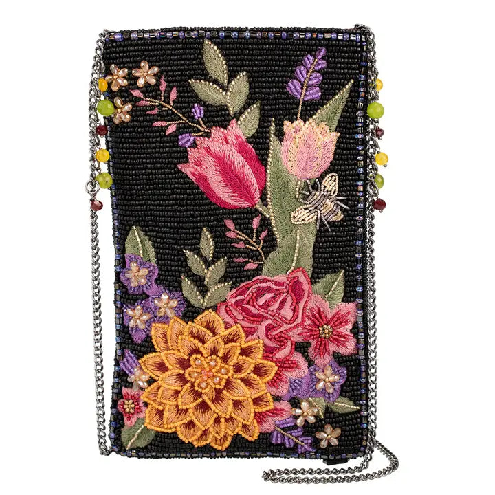 Buzz Bloom Clutch Bag - Compact rectangular cross-body phone bag measuring 5 × 0.5 × 8 inches. The bag features colorful floral embroidery and hand beadwork in shades of orange, red, purple, green, yellow, and ivory against a black beaded background. It includes a top slip pocket, a side zippered compartment, a removable metal chain strap, and a metal logo fob. Handmade, each bag is a unique work of art.