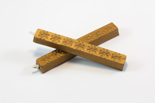 The image shows two 4‑inch dark antique gold wax sticks on a white background, with an aged bronze look. The wax feels hard and smooth, with subtle daisy‑like embossed patterns. When melted, it becomes thick and pliable, then cools to a slightly flexible, buttery finish designed to resist cracking in the mail.