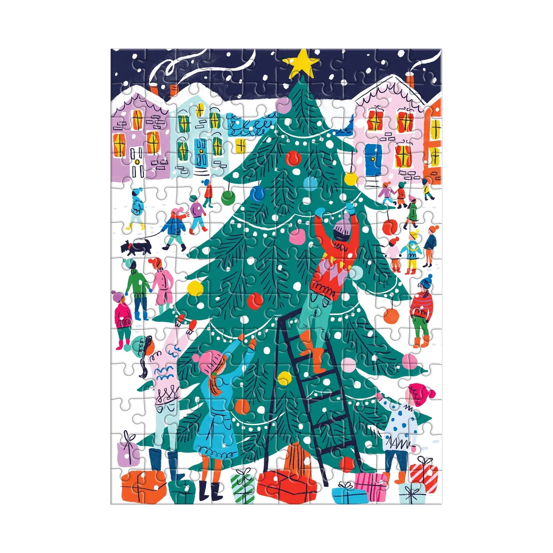 The image shows a completed puzzle from the small red cardboard house, forming a bright winter scene. Children play in the snow in front of pastel‑colored houses. In the center foreground stands a large green Christmas tree decorated with white lights and colorful ornaments. A boy is halfway up the tree on a ladder while other children decorate below, with wrapped gifts scattered across the snowy ground.