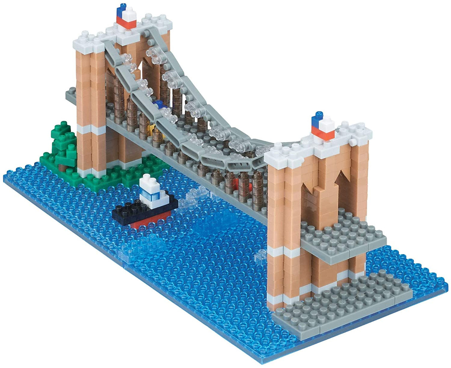 Product title: Brooklyn Bridge Mini Blocks. 
A small Brooklyn Bridge model built from lightweight plastic bricks. Two brownish‑grey towers with arched openings support a flat roadway, with thin pieces forming the diagonal suspension cables. The simplified block style creates a compact, recognizable bridge set on a blue base showing the East River and a small tugboat beneath.