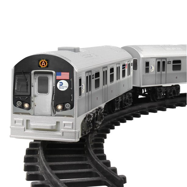 The image shows a gray and black subway train positioned on a curved black track. The front of the train displays small decals, including the MTA logo, an American flag, and a circular symbol above the door with the letter “A” inside.