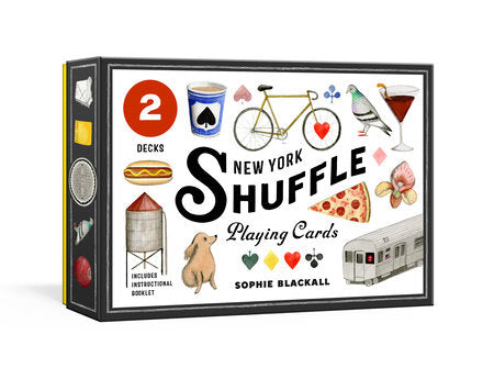 New York Shuffle Playing Cards - the box is a small, rectangular package with smooth, flat sides and no raised texture. The front features a bright, colorful illustration by Sophie Blackall printed completely flat. The artwork shows playful New York–themed drawings—such as a subway, a slice of pizza, pigeon, water-tower, hotdog and other iconic New York images—arranged loosely across the surface. The title “New York Shuffle” appears in clear, bold lettering at the center, also flat to the touch. 
