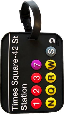 A black PVC MTA Times Square luggage tag with bold, bright details in white, red, fuchsia, yellow, and gray. A white horizontal line sits at the top, followed by “Times Square–42 St Station” in bold white text. Below, colorful circles contain the subway lines, shown with raised numbers and letters, with the MTA logo on the lower right side. A side loop lets you easily attach it to your bag or luggage.