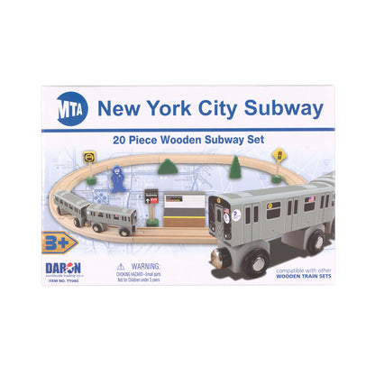 The image shows the package for the New York City Subway 20‑Piece Wooden Subway Set. On the front of the box, the set’s pieces are shown as they would look when arranged for play: two subway cars, wooden tracks, a platform, a conductor figure, trees, and several signal signs. In the lower right corner of the package design, there is a close‑up image of a silver‑gray train car with black wheels, silver rims, and a front connector.