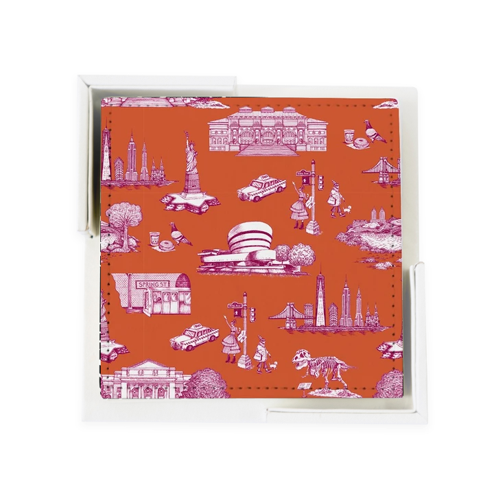 A set of flat, 4-inch square coasters made from smooth,  vegan leather. Each coaster has a orange background printed with delicate line drawings in magenta inspired by classic toile patterns. The illustrations show small New York City scenes—tiny buildings, bridges, trees, and people—arranged like a repeating story across the surface. The set comes with a simple white holder that feels like a small open box.