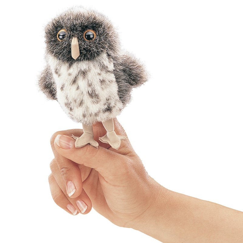 The Mini Spotted Owl Finger Puppet is made of soft plush fabric in warm brown tones, with cream‑colored spots mottled across its body to mimic feathers. Its face is lighter, mostly cream or tan, making the features stand out. The owl has big, bright yellow eyes with black pupils, and a small dark beak at the center. Its wings and back are patterned in darker browns, adding contrast and giving it the look of a tiny, speckled forest owl. 