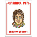 A one inch enamel pin in the shape of an illustrated portrait of John Lennon. 
